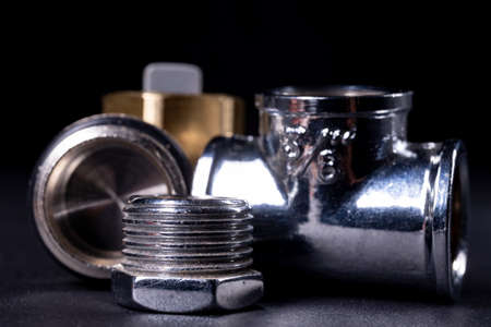 Metal plumbing fittings used to repair the water system. Accessories and spare parts for mechanics. Dark background.の写真素材