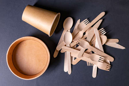 Disposable wooden cutlery and cardboard containers. Accessories for eating outdoors. Dark background.の写真素材