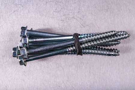 Long wood screws on a metal table top. Accessories for the assembly of wooden elements. Light background.の写真素材