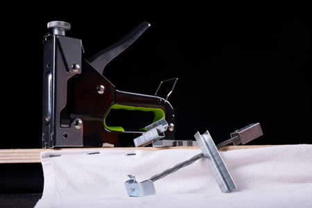 Upholstery stapler, staples and fabric in a carpentry workshop. Accessories, fabrics and tools for...