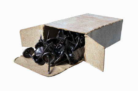 Black push pins in a gray cardboard box. Accessories for upholstery work in the workshop. Dark background.の写真素材