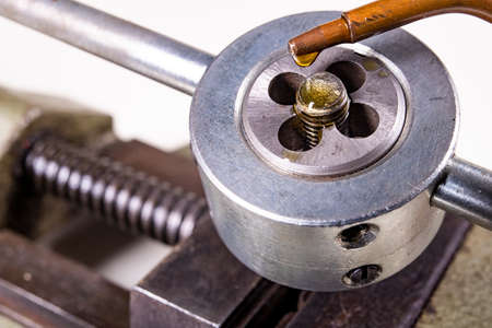 Thread cutting cut in the screw during operation. Oil drops from the oiler on the knife for cutting threads. Isolated background.の写真素材
