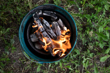 Firing a barbecue in the home garden. Flames floating above charcoal. Spring season.の写真素材