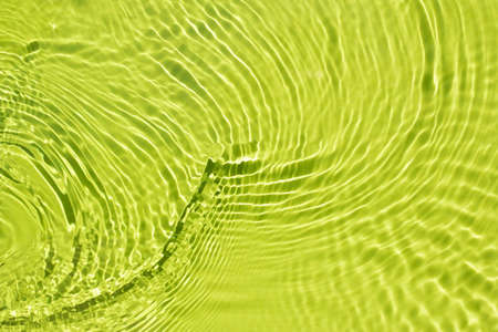 Water spills on a light green background. Natural sunlight and shade. Beautiful bursts, waves, drops, streaks, highlights, glare. Summer mood. Minimal style.の写真素材