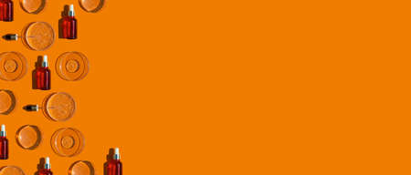 Banner with glass dropper bottles with pipettes and petri dishes on orange background. Medicine and beauty concept. Skincare for face and body. Transparent container with liquid with bubblesの写真素材