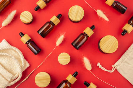 Eco friendly cloth shopping bag and amber glass dropper bottles different sizes with bamboo lid. Zero waste concept. Top view on red background. Skincare natural cosmetic. Beauty concept for face bodyの写真素材