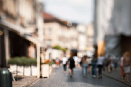 Natural bokeh of old city view, blurred out of focus background. Abstract beautiful backdrop for text or advertising. Unfocused cafes, buildings and peopleの写真素材