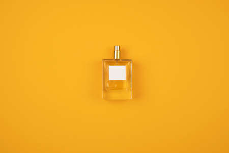 Transparent bottle of perfume with spray on orange surface. Clear glass without lid. Flat lay trending scene with scent. Luxury presentation.の写真素材