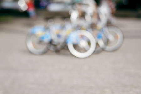 Natural bokeh of bike rental, blurred out of focus background. Abstract beautiful backdrop for text or advertising. Unfocused city viewの写真素材