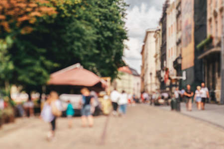 Natural bokeh of old city view, blurred out of focus background. Abstract beautiful backdrop for text or advertising. Unfocused cafes, buildings and peopleの写真素材