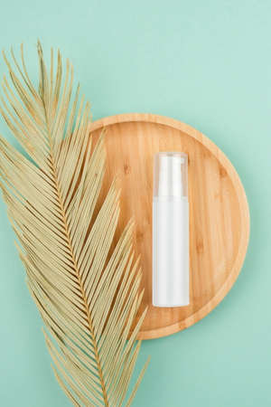 Plastic white bottle with pump for cream or lotion on the wooden podium on mint green background. Top view on light mint green background. Skincare cosmetic. Beauty concept for face body careの写真素材