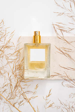Transparent bottle of perfume on stone plate on a white background. Fragrance presentation with...