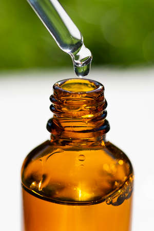 A drop of liquid falling from a pipette into an amber bottle. Skincare products , natural cosmetic. Beauty concept for face and body careの写真素材