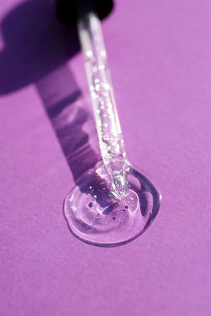 Pipette close-up on a purple background in soft focus. Beautiful shadow in the sunlight. Skincare products , natural cosmetic. Beauty concept for face and body careの写真素材