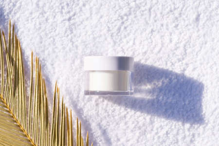 White glass jar against the background of a white towel. Skincare products , natural cosmetic with palm leavesw. Beauty concept for face body careの写真素材