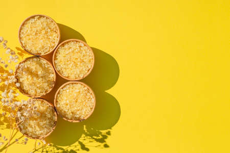 Wooden bowls filled with yellow bath sea salt. Beauty treatment for spa and wellness with plant shadow. Skincare natural cosmetic concept for body care. Place for textの写真素材