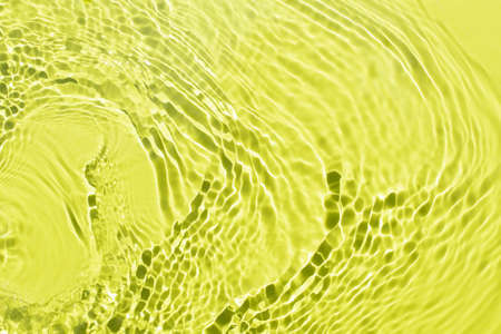 Water spills on a light green yellow background. Beautiful bursts and glare. Summer mood. Minimal style. Natural sunlight and shade. Backdrop for cosmetic ideasの写真素材