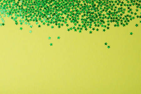 Confetti in the form of stars on green background. Festive day backdrop. Flat lay style with...
