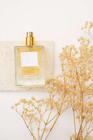 Transparent bottle of perfume on stone plate on a white background. Fragrance presentation with...