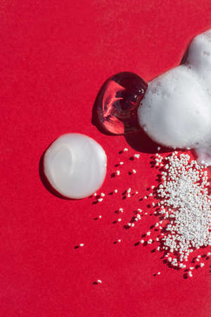 Cosmetic smears and drops. Appearance of the texture of the cream, oil and granules on a red background. Natural skincare products. Beauty concept for face and body careの写真素材
