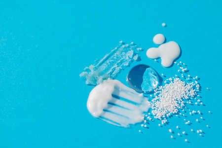 Cosmetic smears and drops. Appearance of the texture of the cream, oil and granules on a blue background. Natural skincare products. Beauty concept for face and body careの写真素材