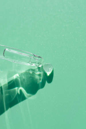 Pipette close-up on a light green background in soft focus. Beautiful shadow in the sunlight. Skincare products , natural cosmetic. Beauty concept for face and body careの写真素材