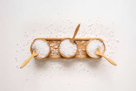 Wooden bowls filled with white bath sea salt. Beauty treatment for spa and wellness. Skincare...