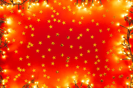 Red background with golden confetti in the form of stars. Valentines, Christmas or New Year day...