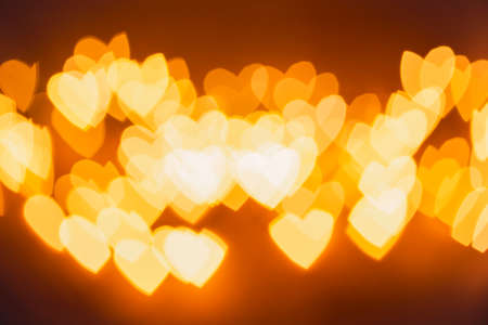 Natural yellow bokeh of lights in the form of a heart, blurred out of focus background. Abstract beautiful backdrop for text or advertising. Postcard with loveの写真素材