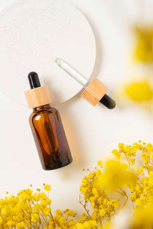 Amber glass dropper bottles with bamboo lid and open pipette with serum or essential oil on white concrete podium for product presentation. Skincare cosmetic. Beauty concept for face body careの写真素材