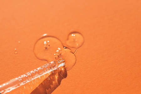 Pipette close-up on a orange background in soft focus. Beautiful shadow in the sunlight. Skincare...