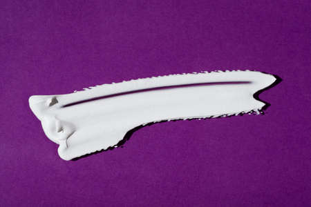 A smear of cream or face mask. The appearance of the texture of the cream on purple background....