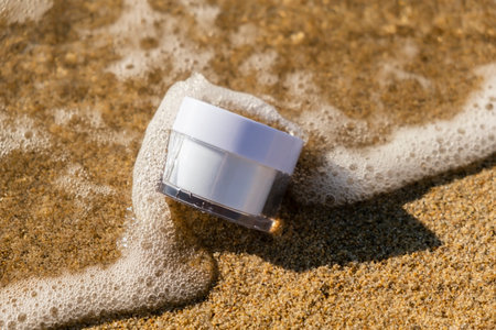 White jar of cosmetic producton the sea sand. Beauty concept for face body care. Travel vacation and sun protection accessory. Skin care in summer day on the beach. Face moisturizing creamの写真素材