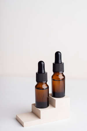 Amber glass bottles with dropper pipette with serum or essential oil on concrete plate for product presentation. Skin care cosmetic. Beauty concept for face body careの写真素材