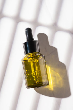 Green glass bottles with dropper pipette with serum or essential oil on a white background. Skincare cosmetic with beautiful shadows. Beauty concept for face body care. Place for textの写真素材