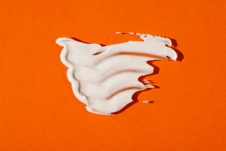 A smear of cream or face mask. The appearance of the texture of the cream on orange background....