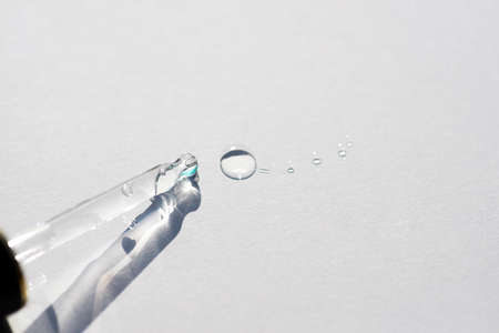 Pipette close-up with drops on the surface on a light background in soft focus. Beautiful shadow in...