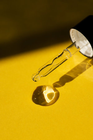 Open cap with close-up dropper pipette with serum. Yellow background with daylight and the appearance of the texture of the gel. Skin care products , natural cosmetic. Beauty concept for face and body careの写真素材