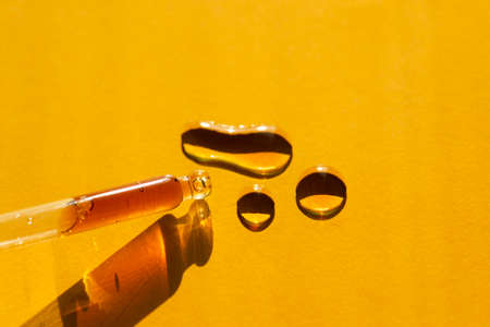 Pipette close-up on an orange background in soft focus. Beautiful shadow in the sunlight. Skincare products , natural cosmetic. Beauty concept for face and body careの写真素材