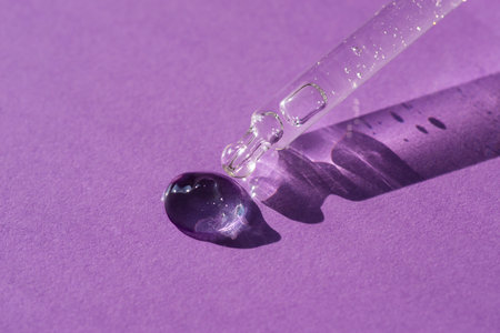 Pipette close-up on a purple background in soft focus. Beautiful shadow in the sunlight. Skincare...