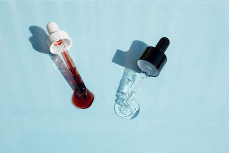 Open caps with dropper pipettes with serum. Blue background with daylight and the appearance of the...