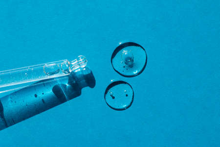 Pipette close-up on a blue background in soft focus. Beautiful shadow in the sunlight. Skincare...
