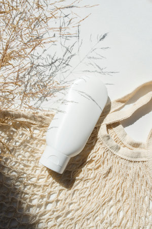Plastic white tube for cream or lotion with cloth shopping bag. Sunscreen cosmetic on white...