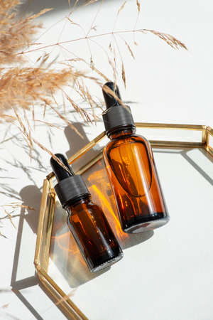 Amber glass bottles dropper pipette with serum or essential oil on glass plate for product...
