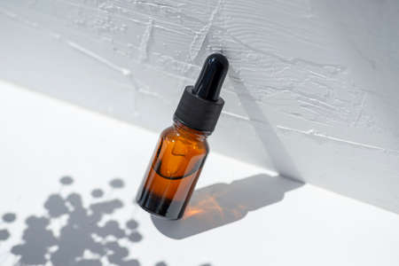 Bottle with dropper pipette with serum or essential oil. White background with daylight and...