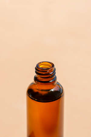 Open transparent bottle without cap with serum or essential oil with beautiful wild grass in soft...