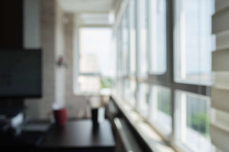 Blurred of home office. Window view, out of focus background. Abstract beautiful backdrop for text or advertising. Unfocused room, computer and tableの写真素材
