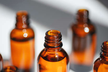 Open amber bottle with serum or essential oil. White background with daylight and beautiful shadows. Beauty concept for face and body careの写真素材