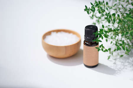 Amber bottle with craft label thyme essential oil. White background with daylight and beautiful shadows. Skincare products, natural cosmetic. Beauty concept for face and body careの写真素材