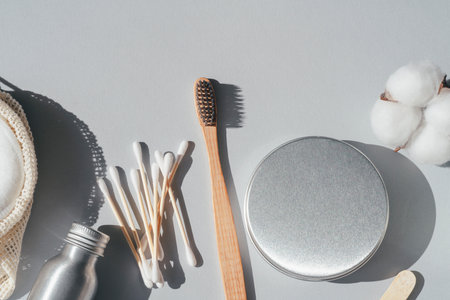 Zero waste concept. Metallic bottle and can, reusable cotton rounds. Packaging for cleaning teeth without plastic. Wooden toothbrush and glass jar with toothpaste on a grey background. Bathroom accessories, oral careの写真素材